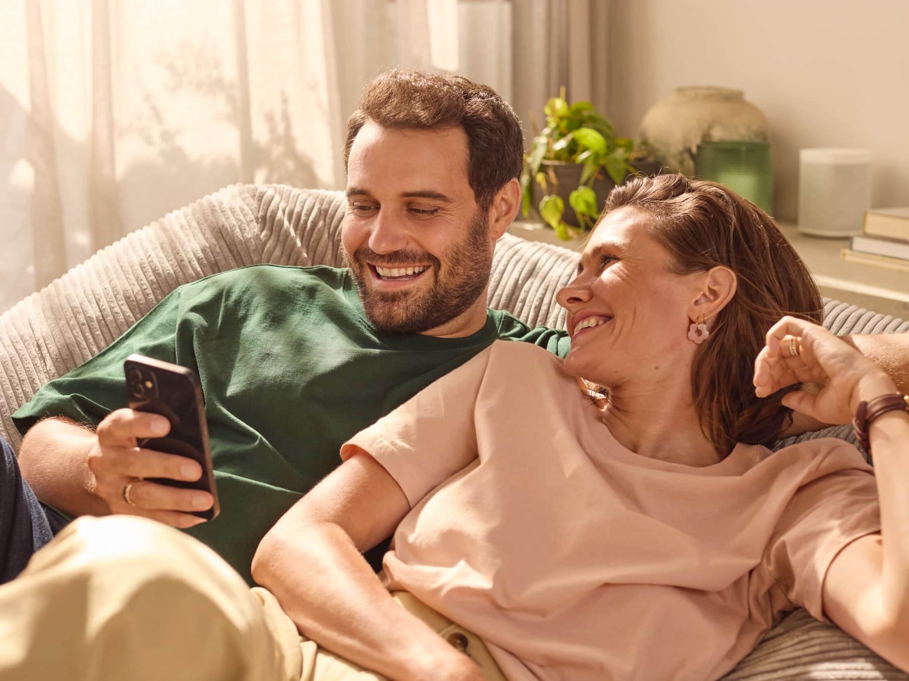 A kanapén ülő pár egy alkalmazáson ellenőrzi az energiafogyasztást