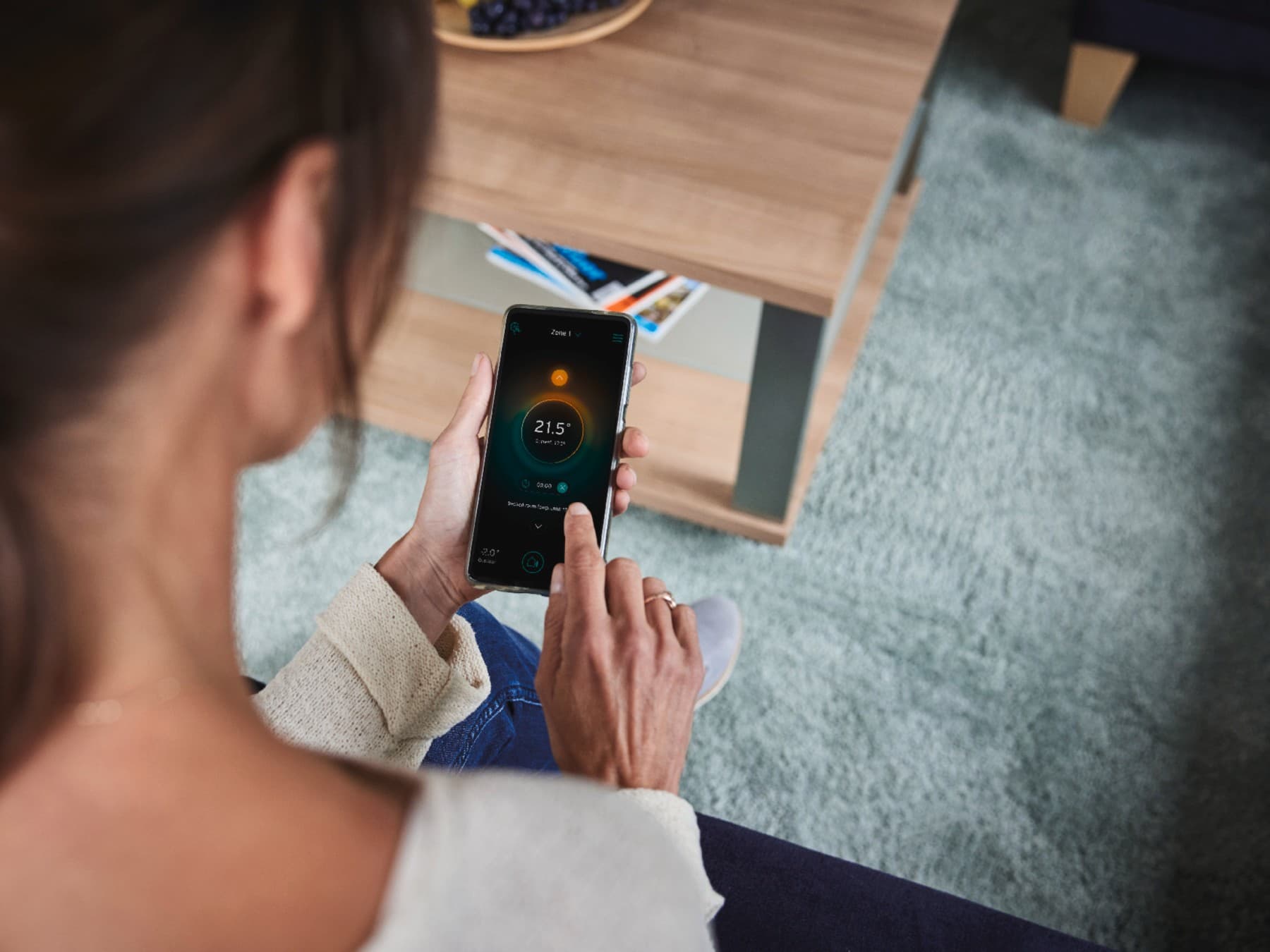 Nő, aki a telefonján állítja be az intelligens rendszerét.